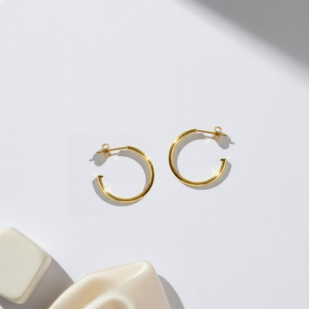 Gold-plated 925 silver hoops from the Enishi collection, minimal yet playful design — flat lay shot.