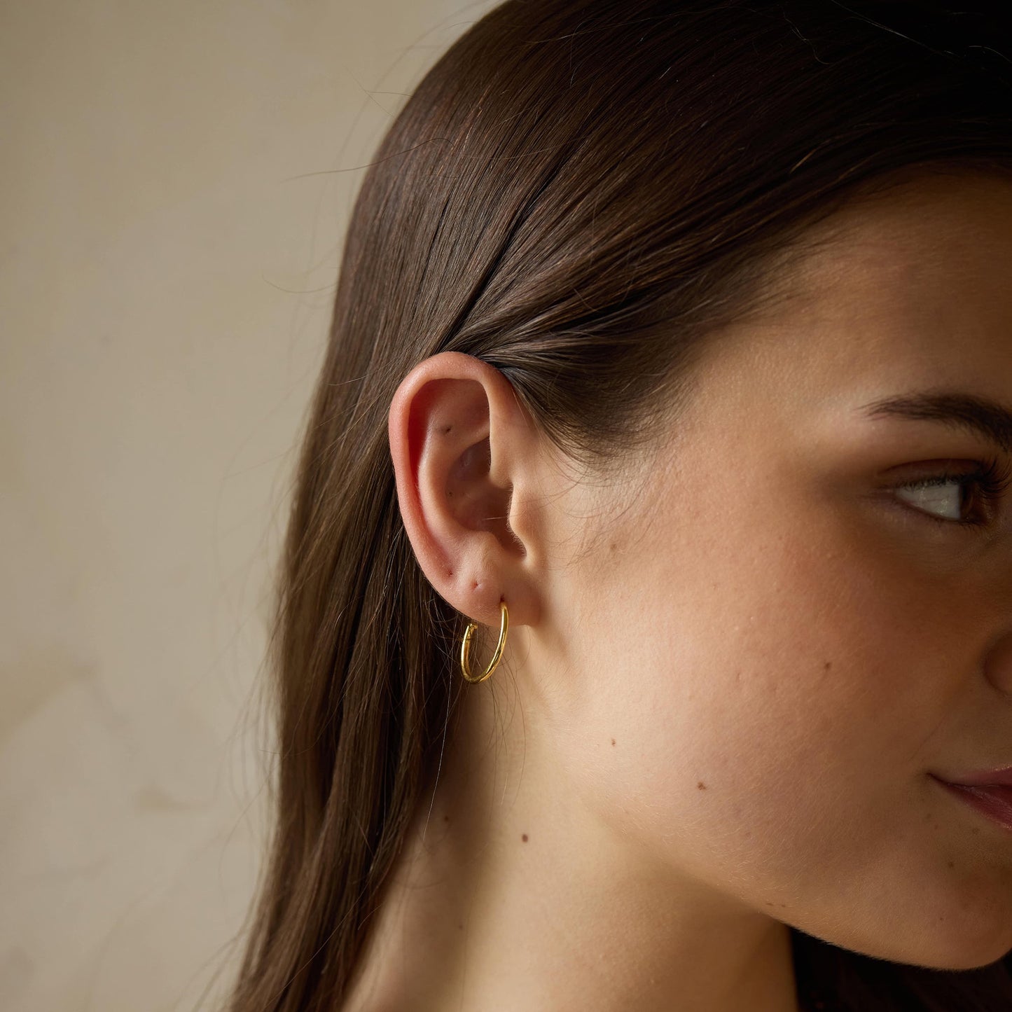 Gold-plated 925 silver hoops from the Enishi collection, minimal yet playful design — model - close-up shot.