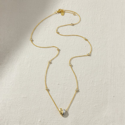 Gold and rhodium organic heart necklace in 925 silver, statement sculptural pendant — flat lay shot.