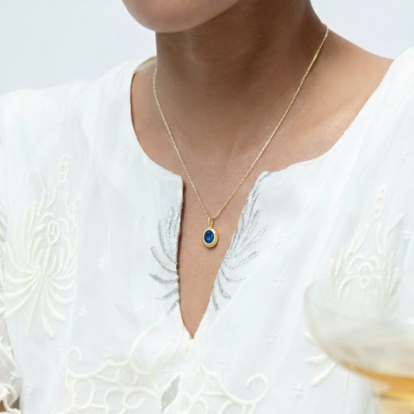 Model Image 1 of KiraKira Oval Sapphire Charm | 925 Silver Gold-Plated from Nishani’s Kira Kira festive collection — handcrafted sapphire jewelry, charm in gold-plated 925 silver.