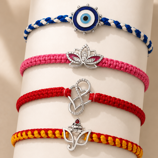 Four braided cord bracelets stacked on a white cylindrical display stand. From top to bottom: a blue and white bracelet with a circular evil eye charm, a pink bracelet with a silver lotus charm, a red bracelet with a silver infinity symbol, and a yellow and red bracelet with a silver crown charm.