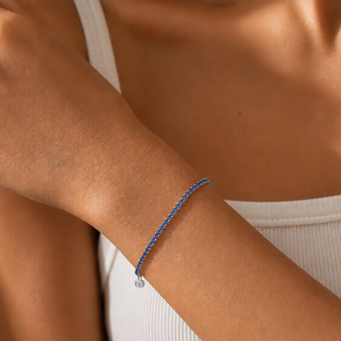 Close-up of a person wearing a blue bracelet on a neutral background