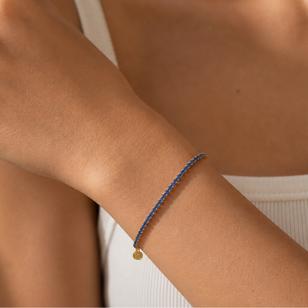 Close-up of a wrist wearing a blue beaded bracelet with a gold charm.