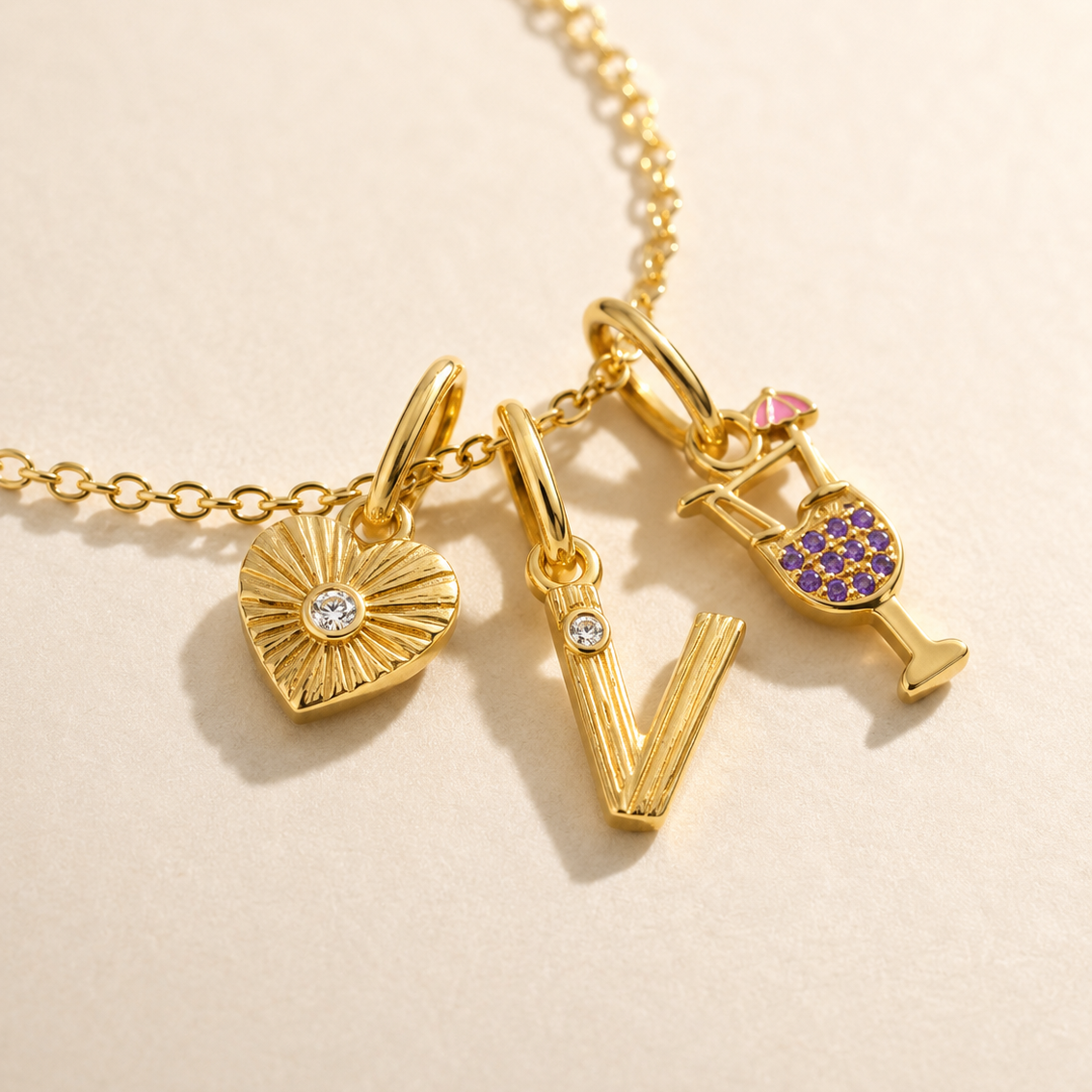 Gold necklace with various charms on a beige background