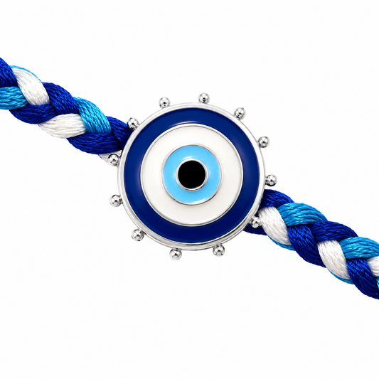 A blue and white braided cord bracelet with a central evil eye charm featuring blue, white, and silver details, set against a plain white background.