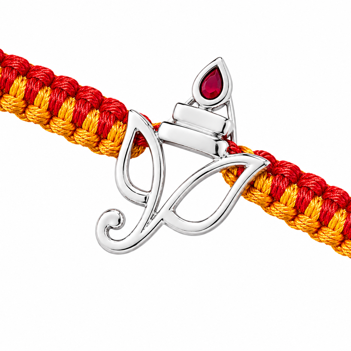 A close-up of a braided cord bracelet in red and yellow with a polished silver-toned diya pendant featuring a red teardrop stone, set against a plain white background.