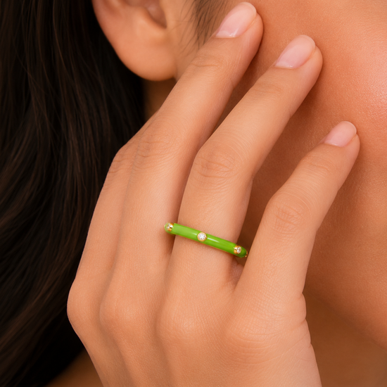 Close-up of a hand with a green ring on a blurred background
