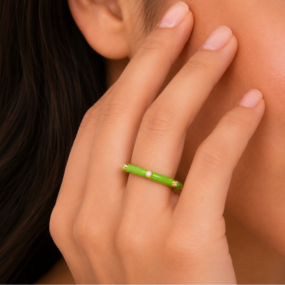 Close-up of a hand with a green ring on a blurred background