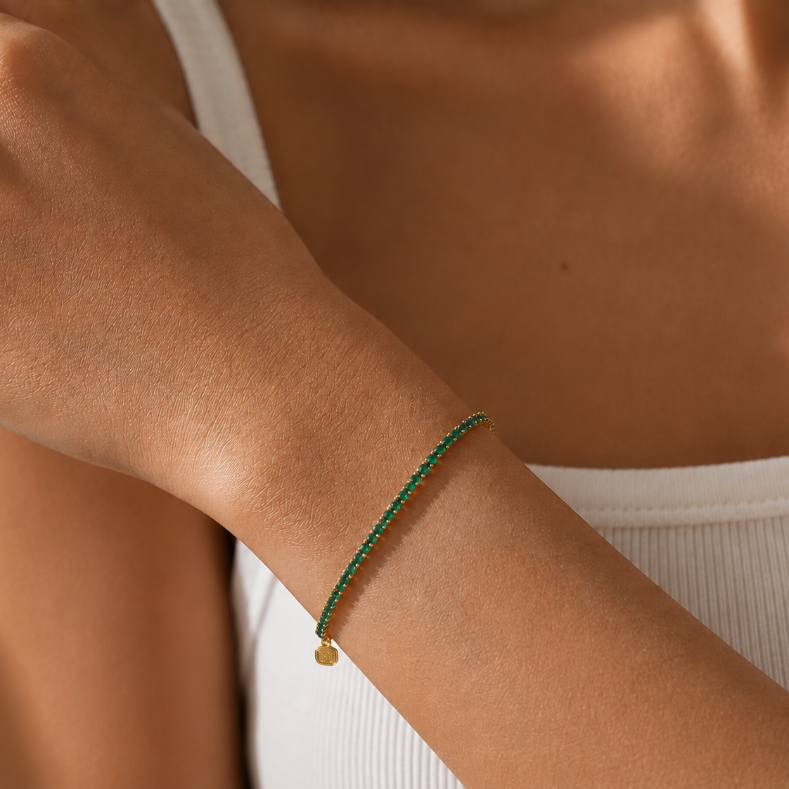 Close-up of a person's arm wearing a green bracelet with a small gold charm.