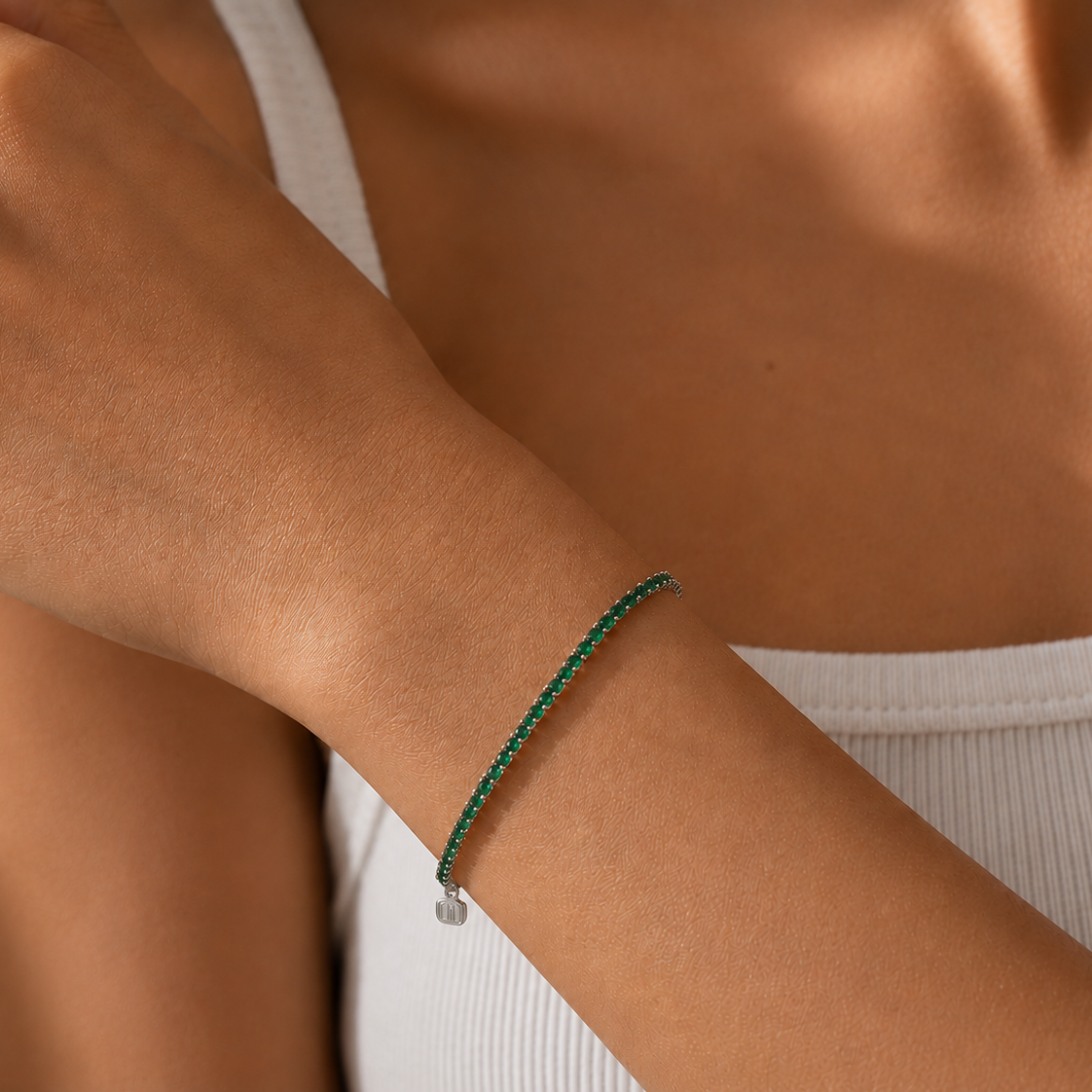 Close-up of a person's arm wearing a green bracelet on a neutral background