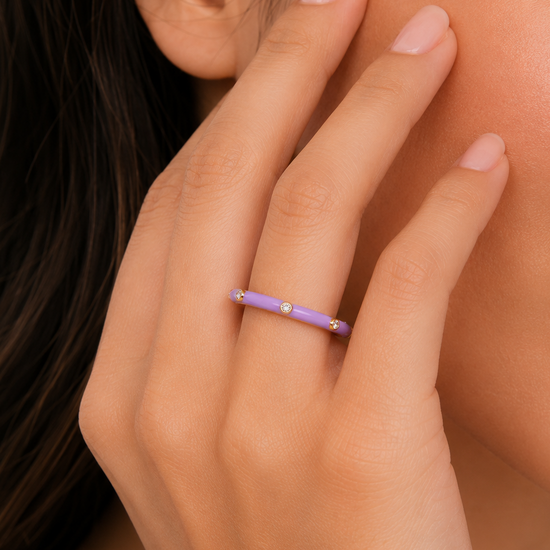 Close-up of a hand wearing a purple ring with a blurred background