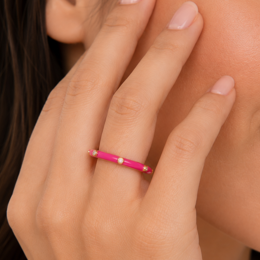 Close-up of a hand wearing a pink ring on a blurred background