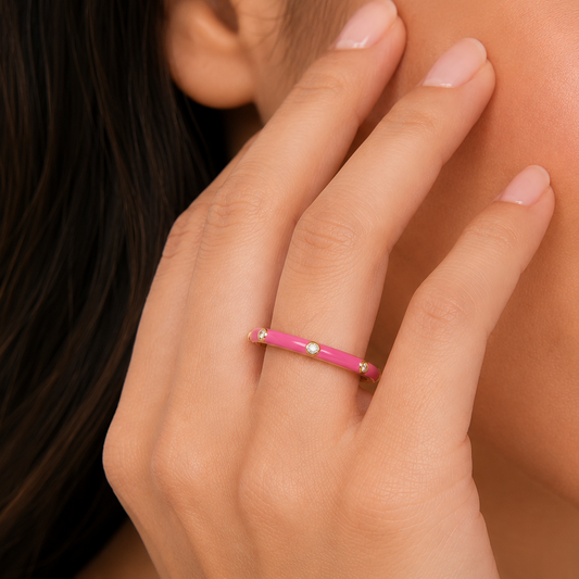 Close-up of a hand wearing a pink ring with a blurred background