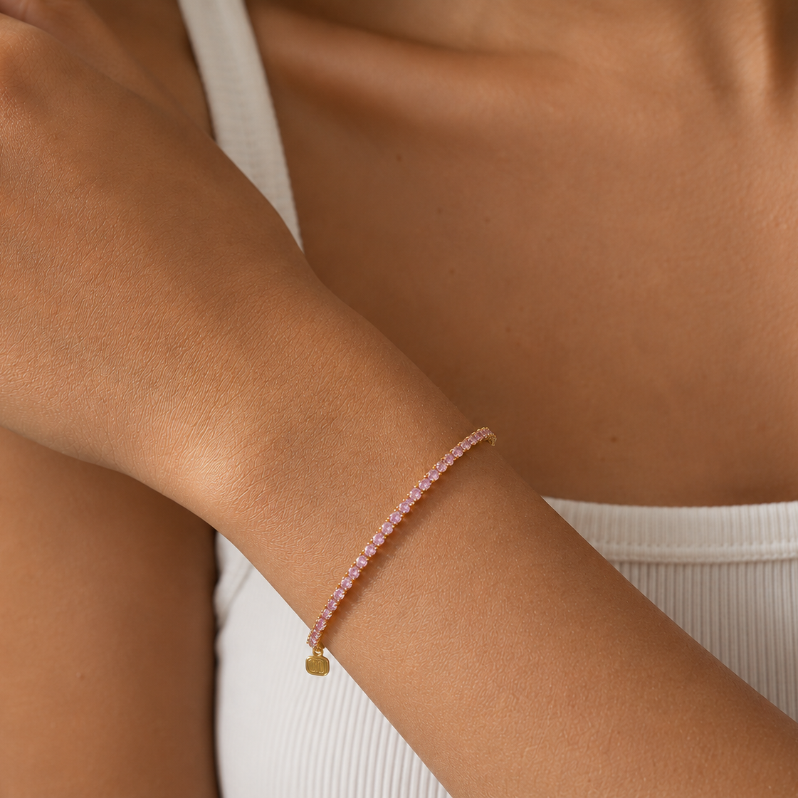 Close-up of a person's arm wearing a pink beaded bracelet on a neutral background