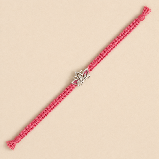 A pink braided cord bracelet with a silver lotus charm set with small clear stones, displayed diagonally on a solid beige background.