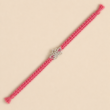 A pink braided cord bracelet with a silver lotus charm set with small clear stones, displayed diagonally on a solid beige background.