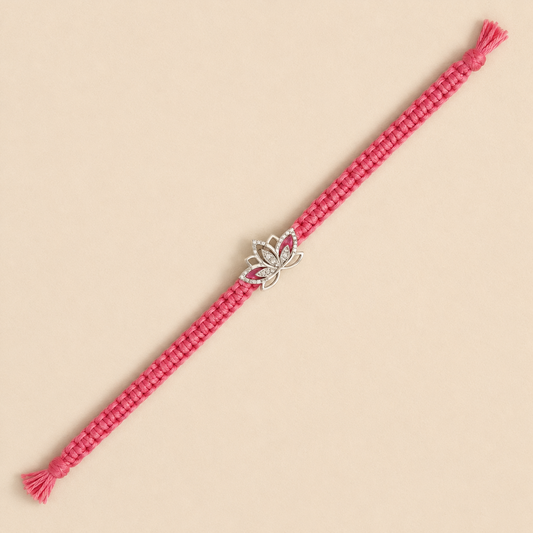 A pink braided cord bracelet with a silver lotus charm set with small clear stones, displayed diagonally on a solid beige background.