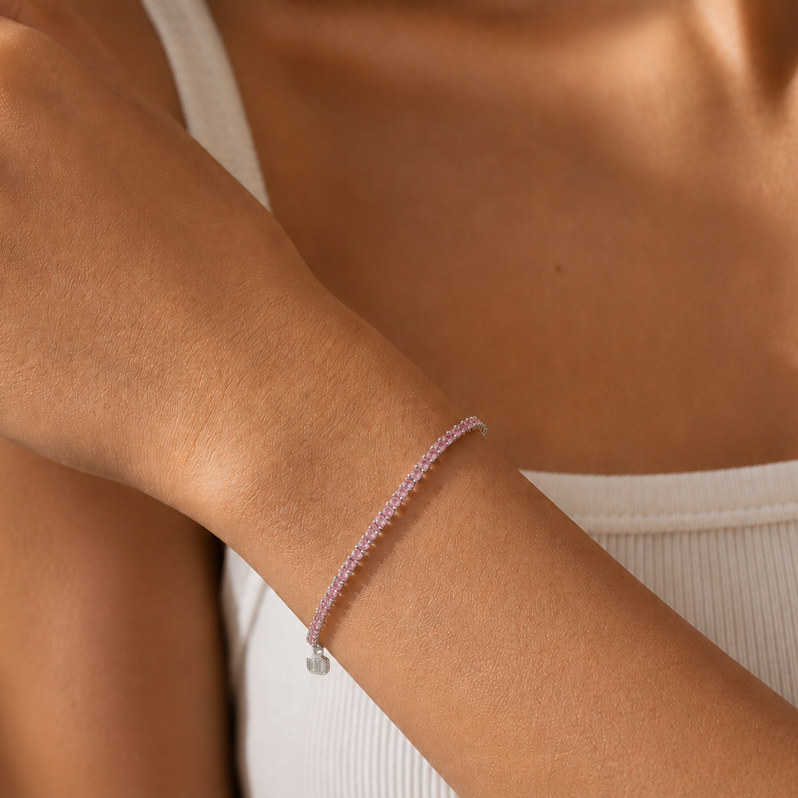 Close-up of a person's arm wearing a delicate bracelet with a small charm.