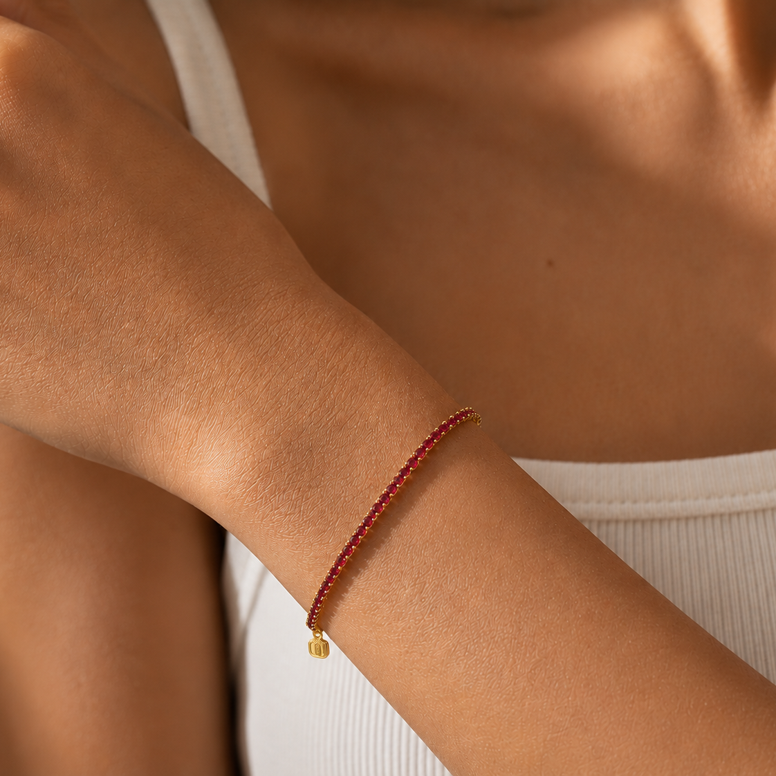 Close-up of a person's arm wearing a red beaded bracelet on a neutral background