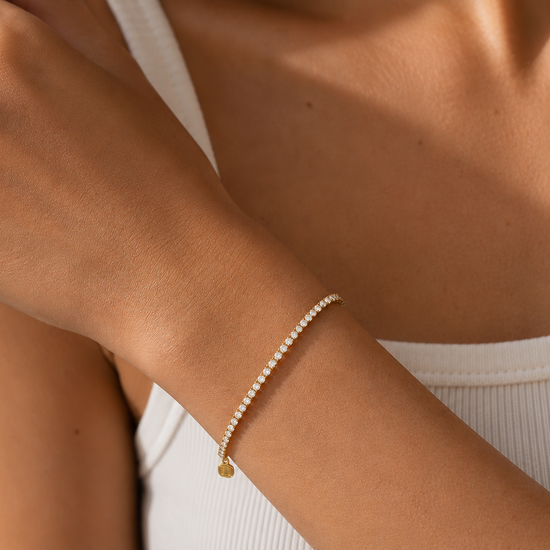 Close-up of a person's wrist wearing a delicate gold bracelet with small beads.